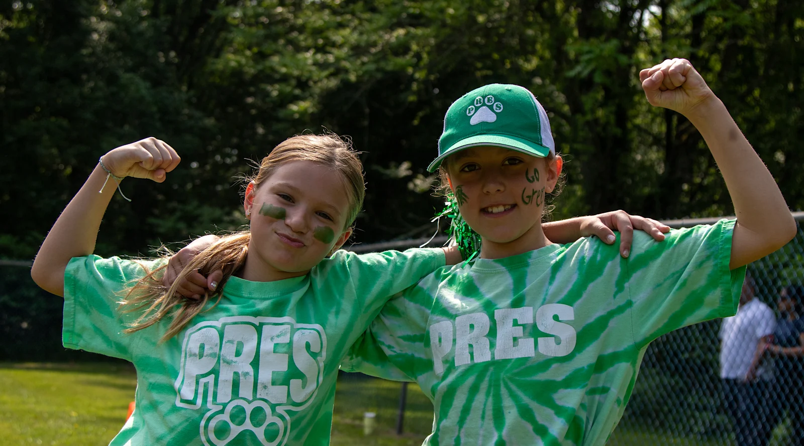 students in matching green spirit wear show their muscles