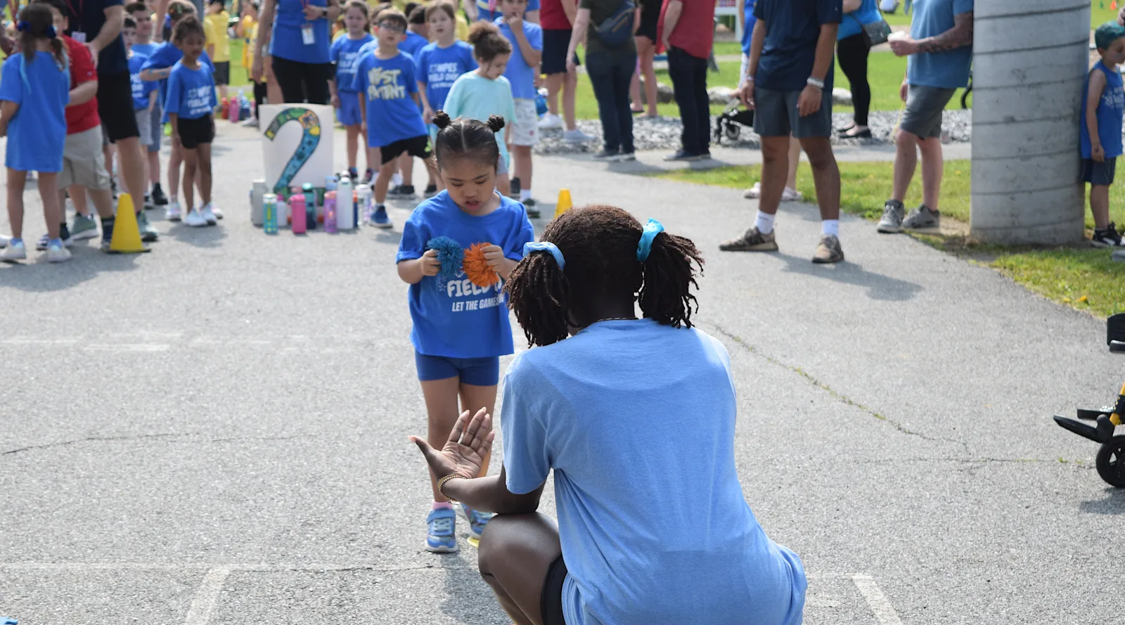 a staff member coaches a student to toss during field day